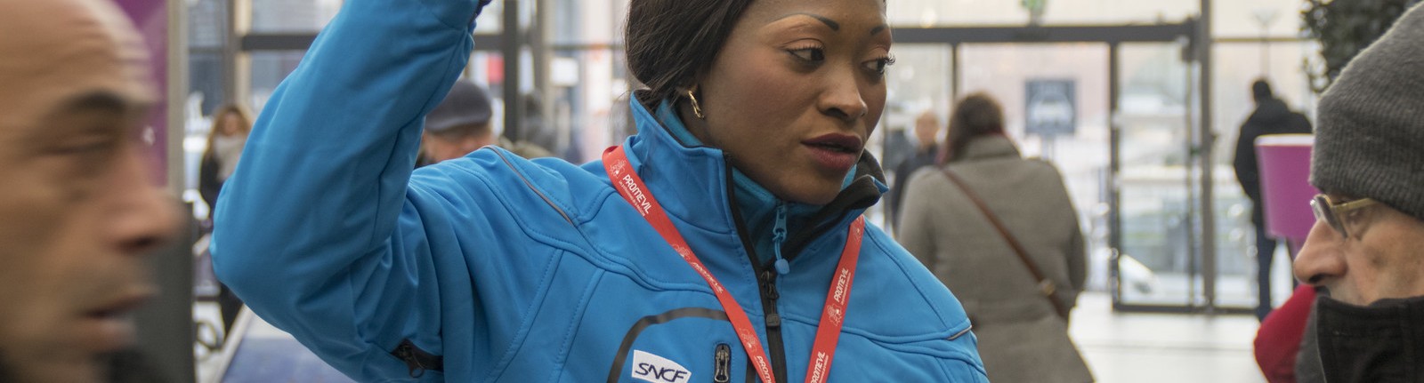 Médiatrice renseignant des voyageurs dans un hall de gare